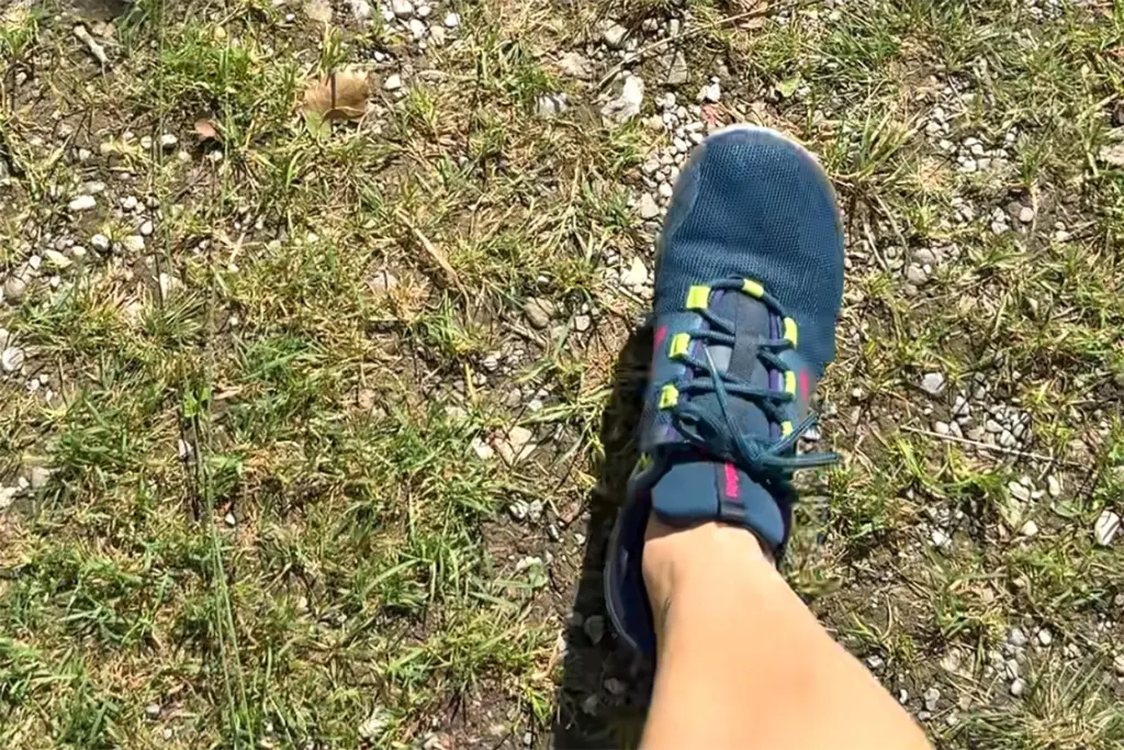 Barfuß laufen mit Minimalschuhen auf einem festen Schotterweg im Park